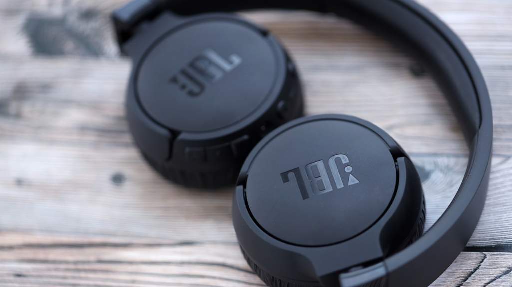 Perbandingan headphone kabel dan headphone nirkabel di atas meja kayu